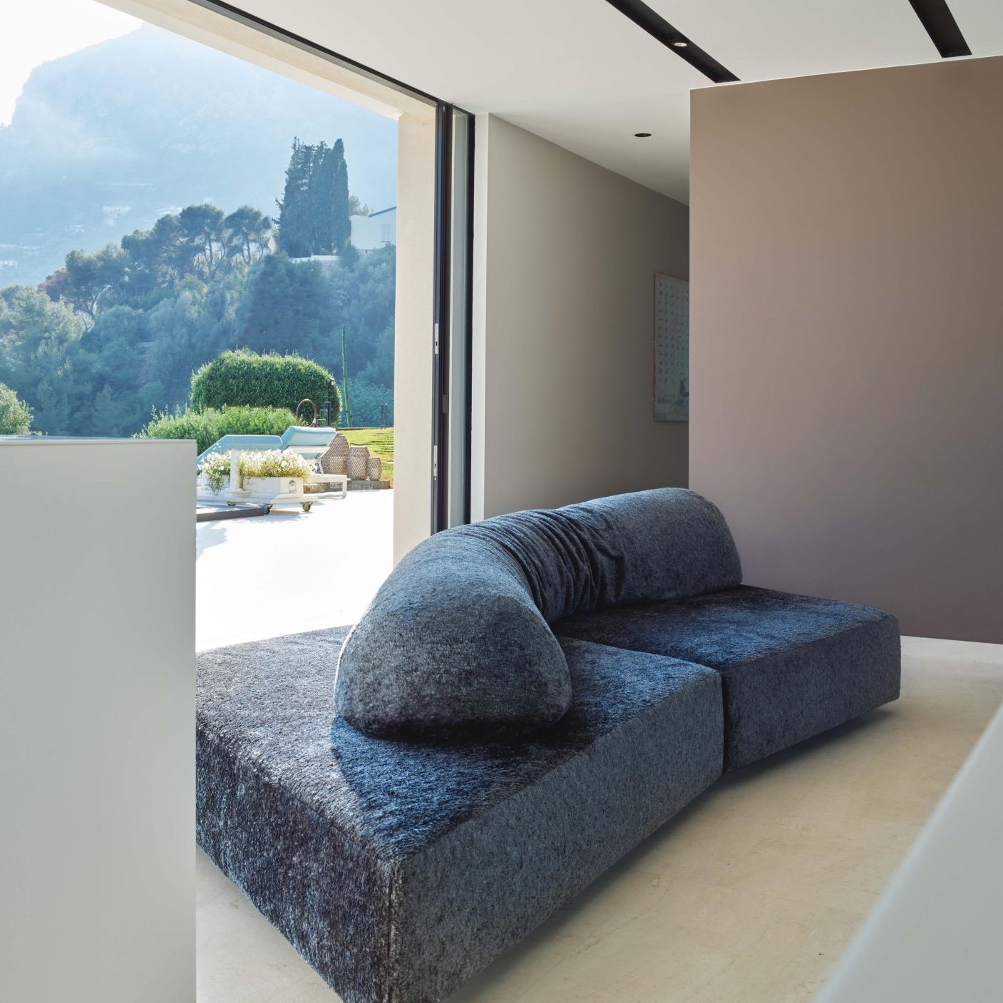   On the Rocks . The sofa positioned in front of the floor-to-ceiling window offers a dual view, overlooking both the interior and the surrounding landscape. 